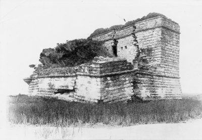 A black and white photograph (dated to 1912) of Fort Matanzas in St. Augustine, Florida. The fort is cracked and ruined — overgrown by marsh trees and grass. 