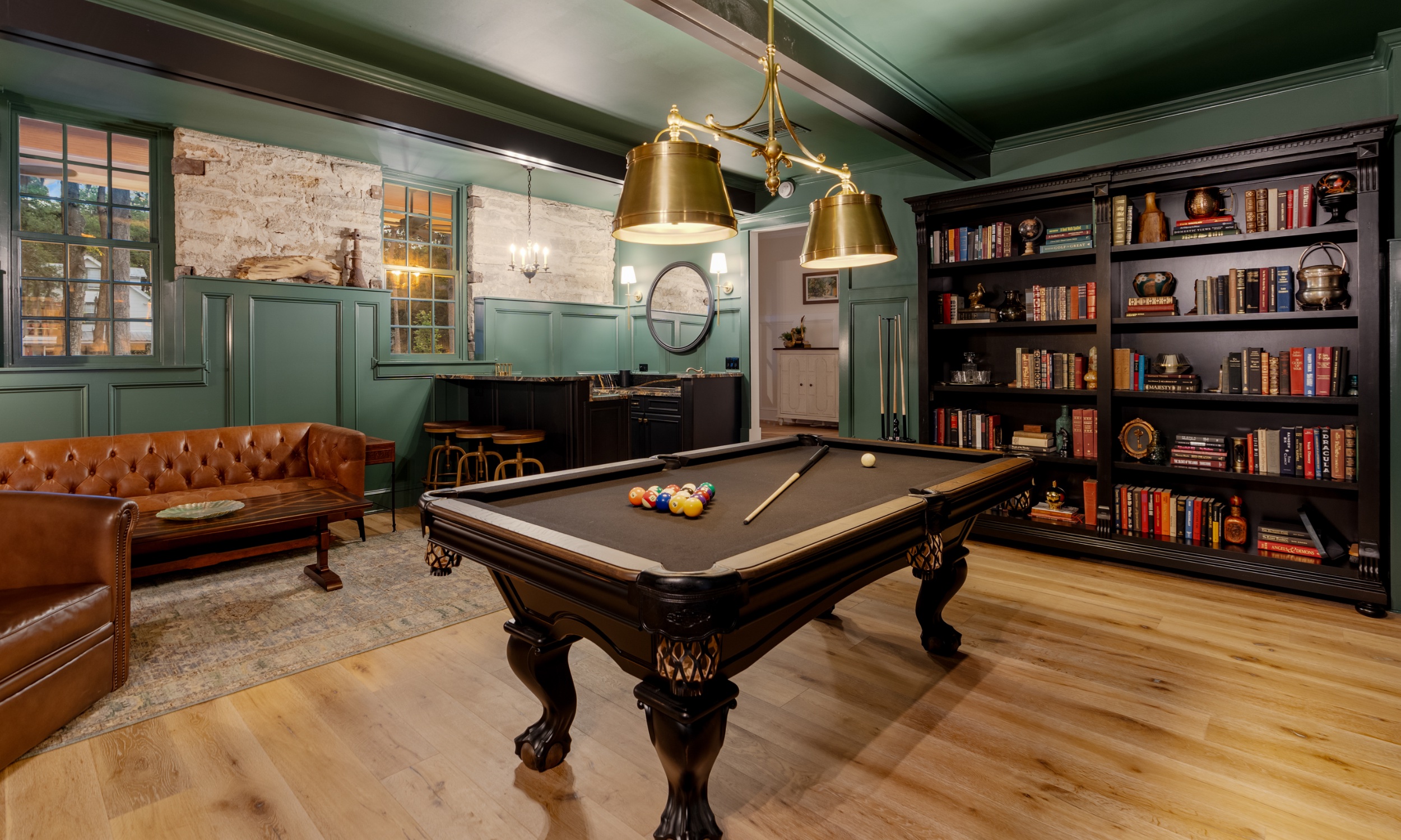 This darkly-painted room includes full book shelves, a pool table, and wet bar