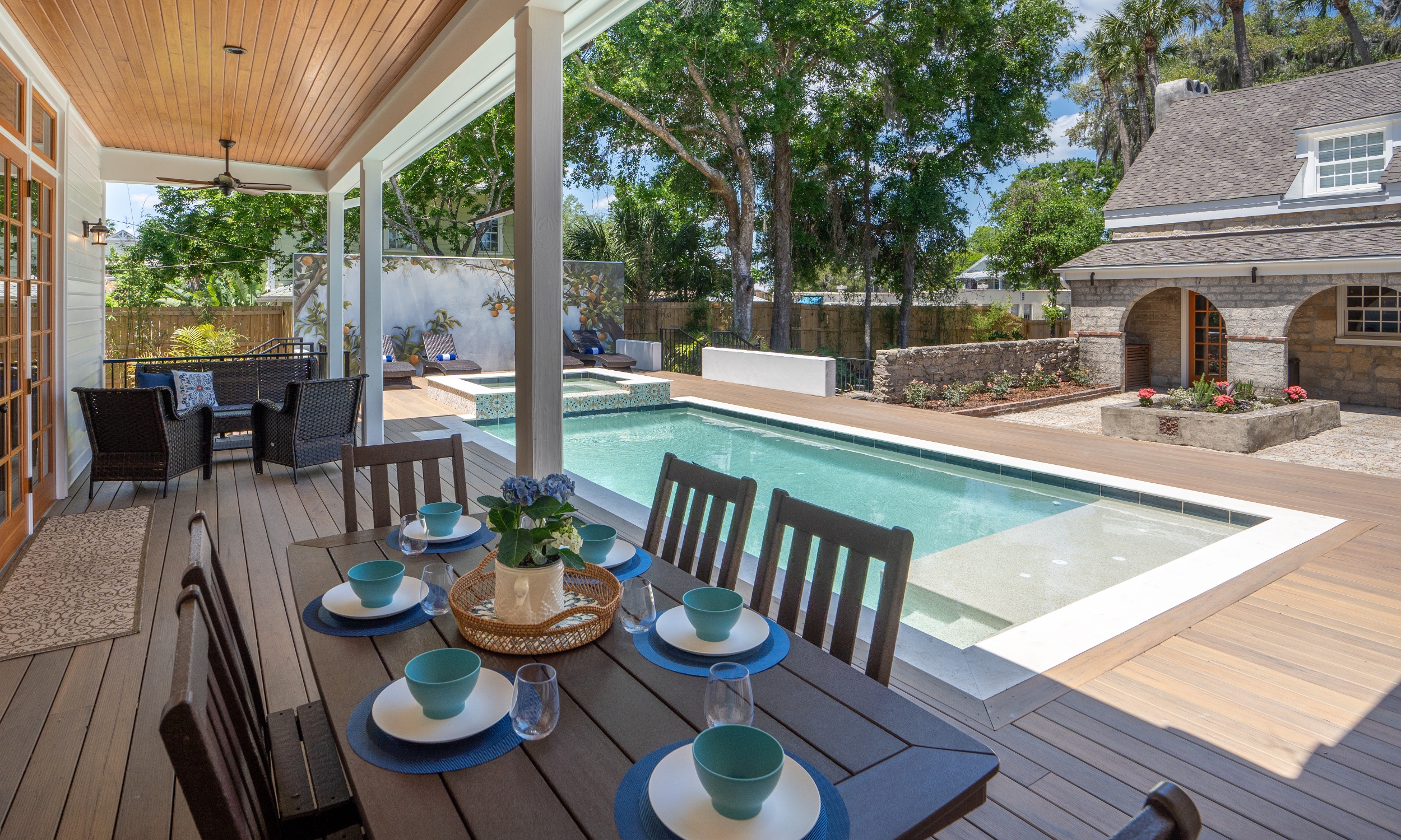 A dining porch and pool deck in a restored historic property on a sunny day
