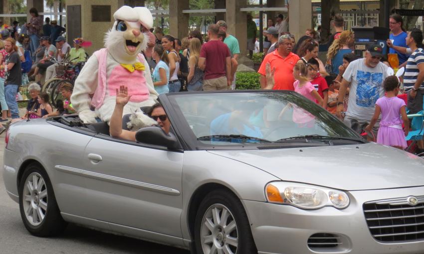 The Easter Bunny greets the crowd while perched on an open silve convertable