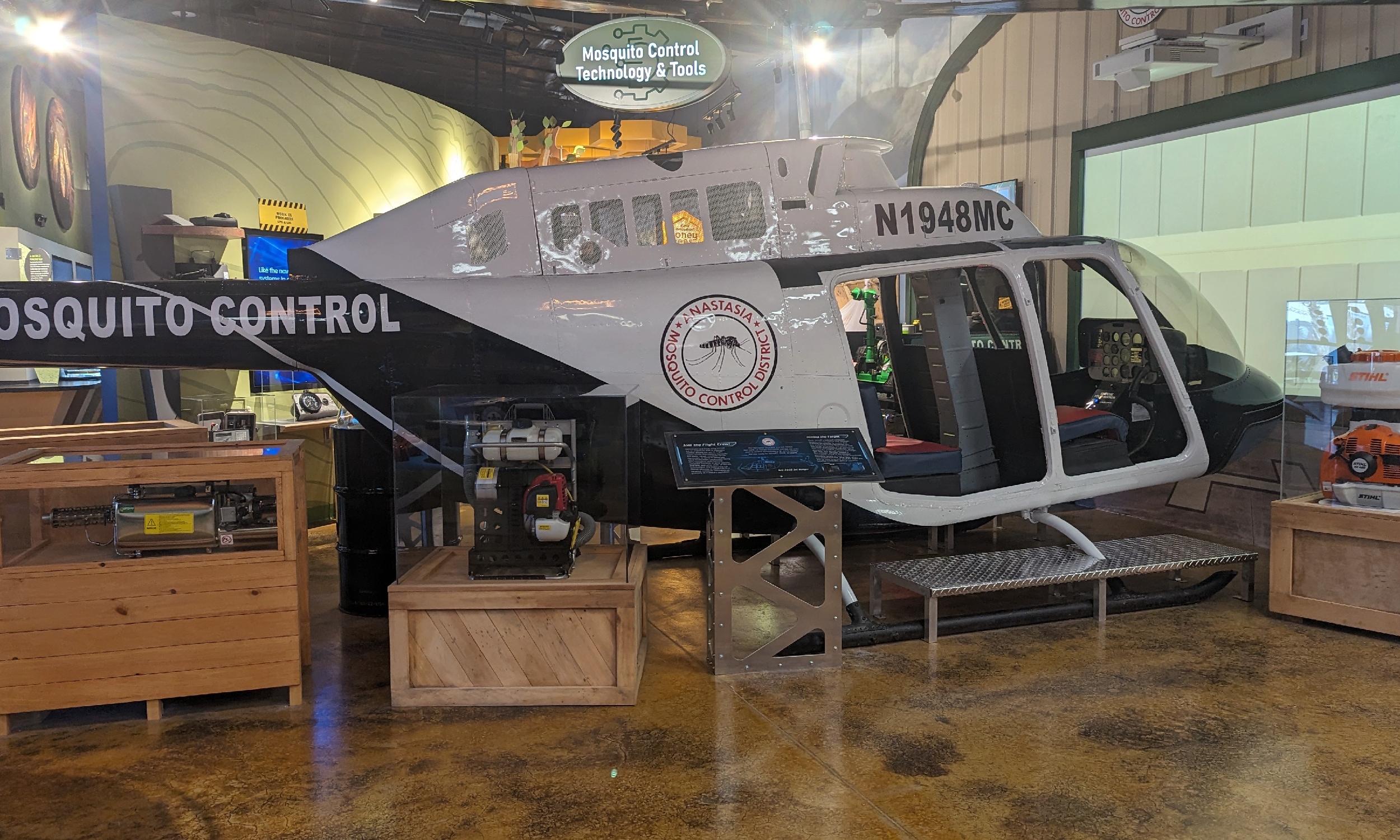 A small helicopter, inside an education center sits with items used to run it