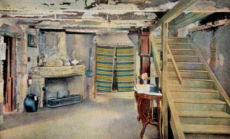 A color-tinted image of an interior room of the Oldest House in St. Augustine, Florida. On the rightside of the image, a staircase ascends to an unseen second floor. In the background, a fireplace of coquina stone can be seen. There are jugs on the mantle and on the floor. A yellow and green patterned fabric covers a doorway to the right of the fireplace.