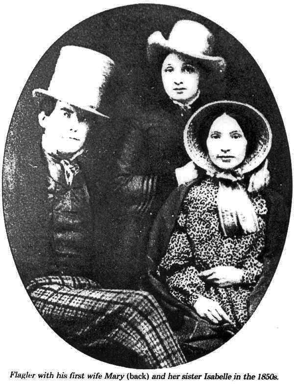 A black and white photograph of poor quality that shows Henry Flagler (foreground, lounging cockily with his plaid-panted legs crossed), Isabella Harkness (right of Henry, staring into the camera with a bonnet on and a blank expression) and Mary Harkness (background) who wears a dandy hat. They are all pale with dark hair and fancily dressed.