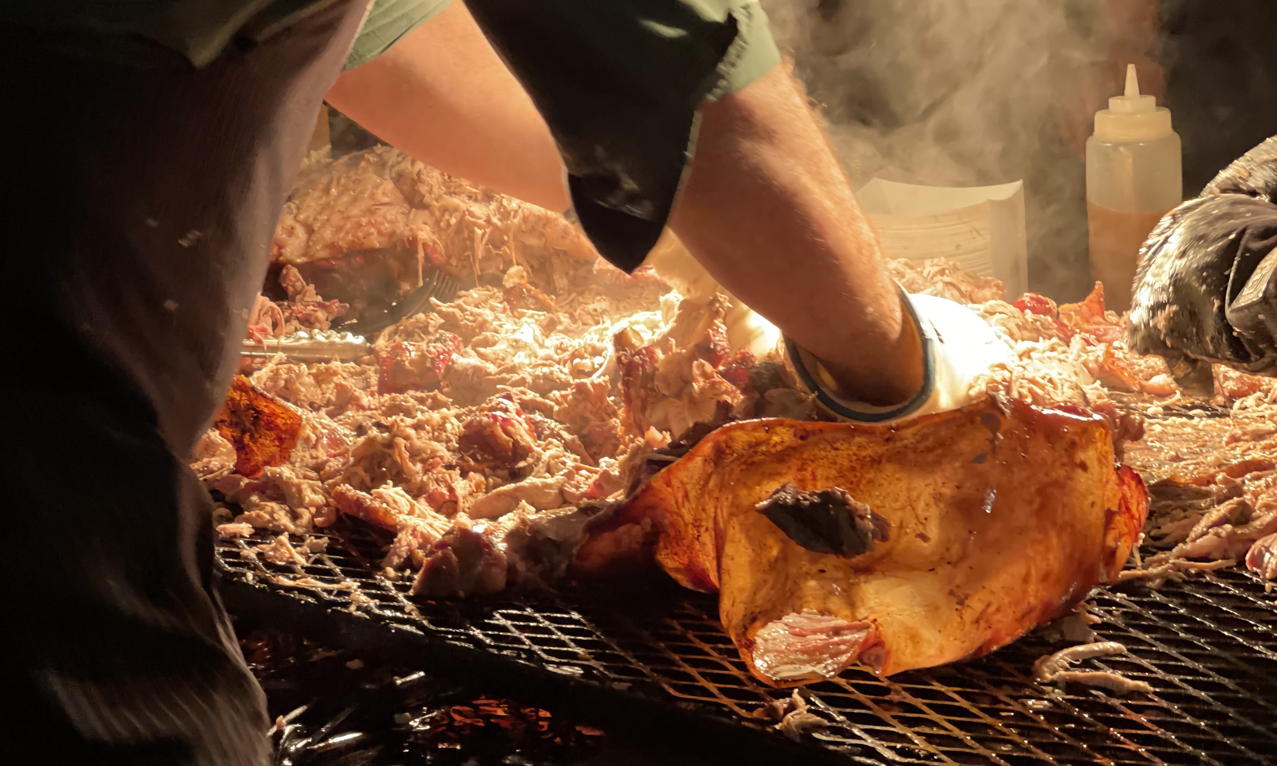 The hands of a grill chef preparing smoked meat for guests