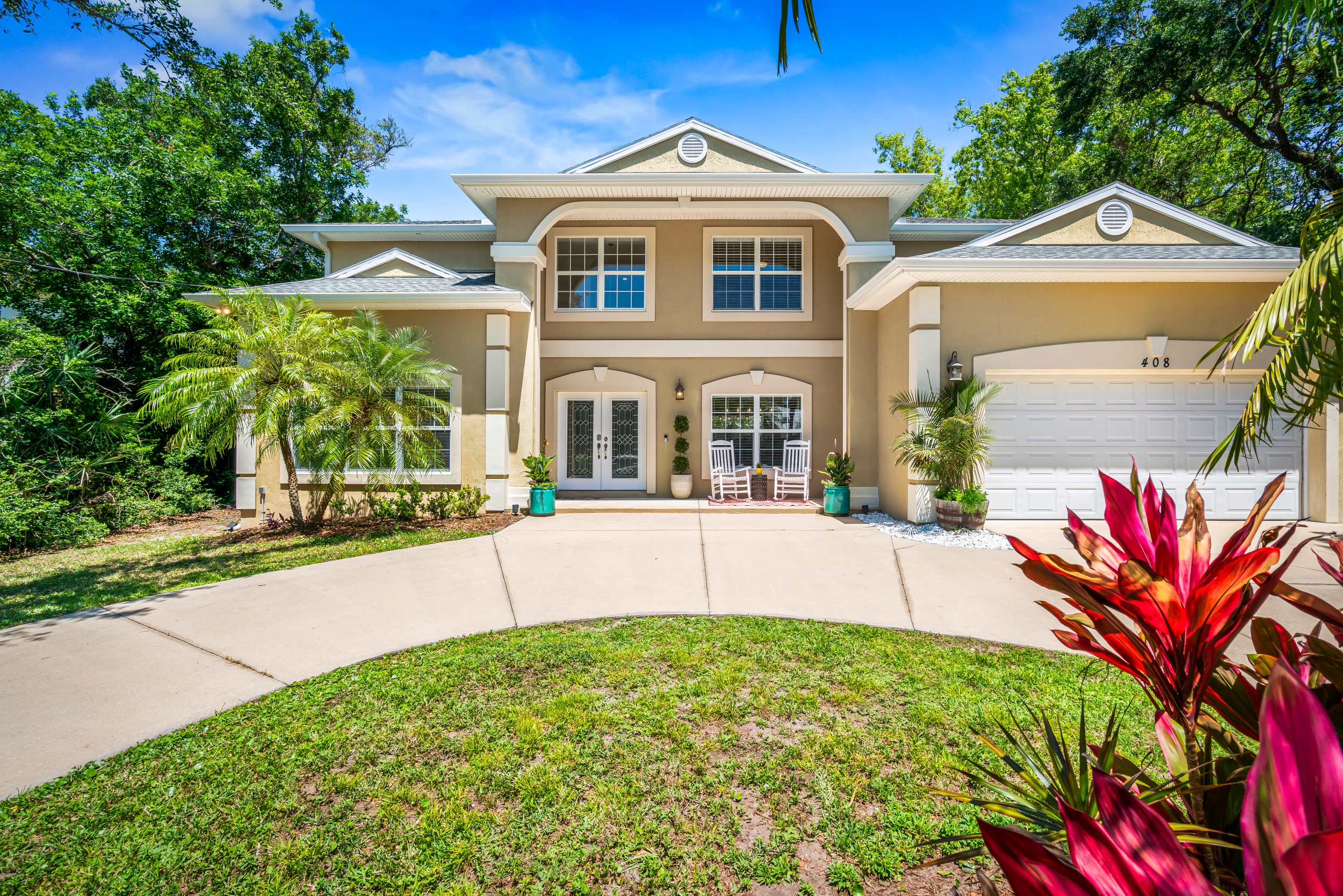 This two-story tan and cream building with circular driveway is Casa Del Sol, a vacation rental available through Vilano Luxury Properties