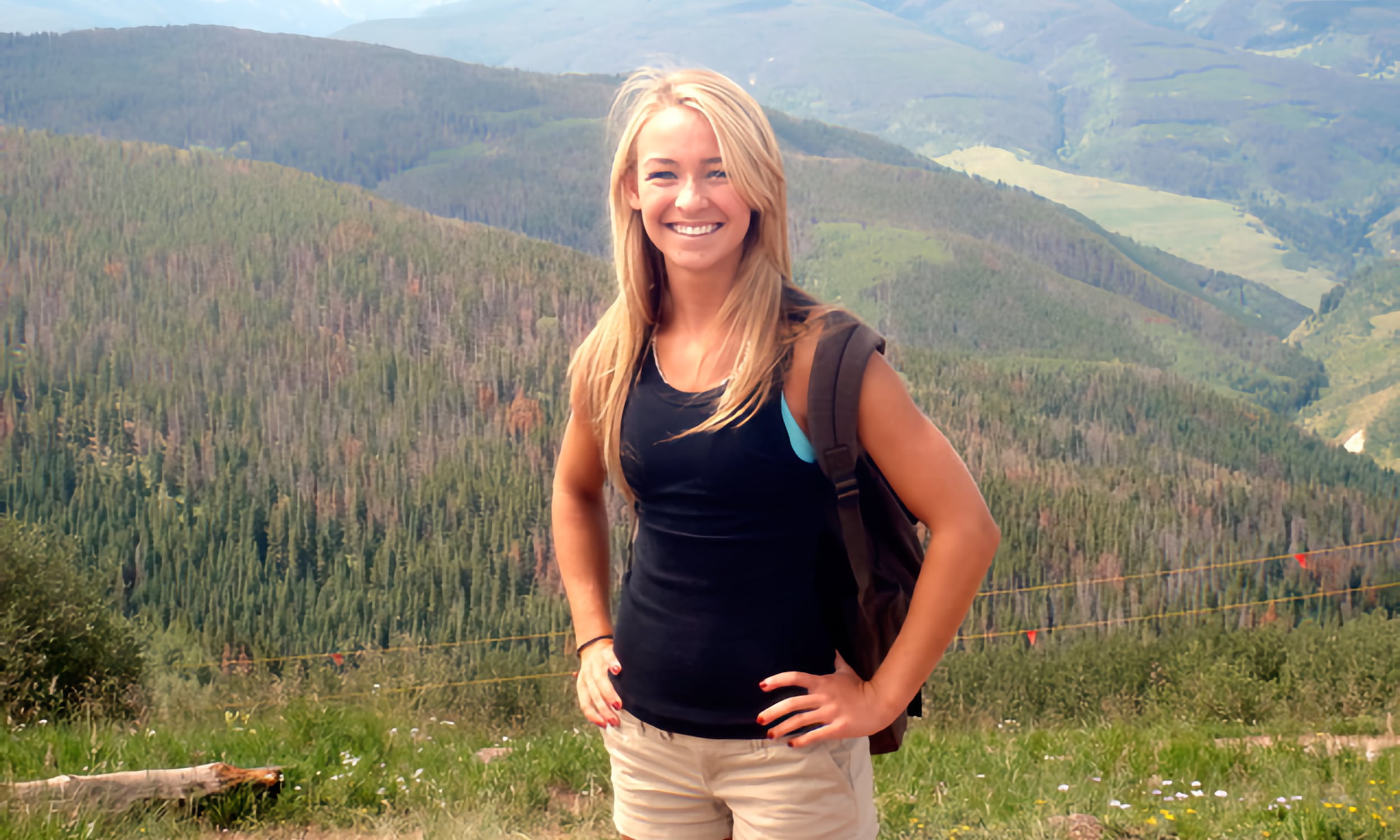 McKenzie Wilson stands in front of forested mountains and valleys