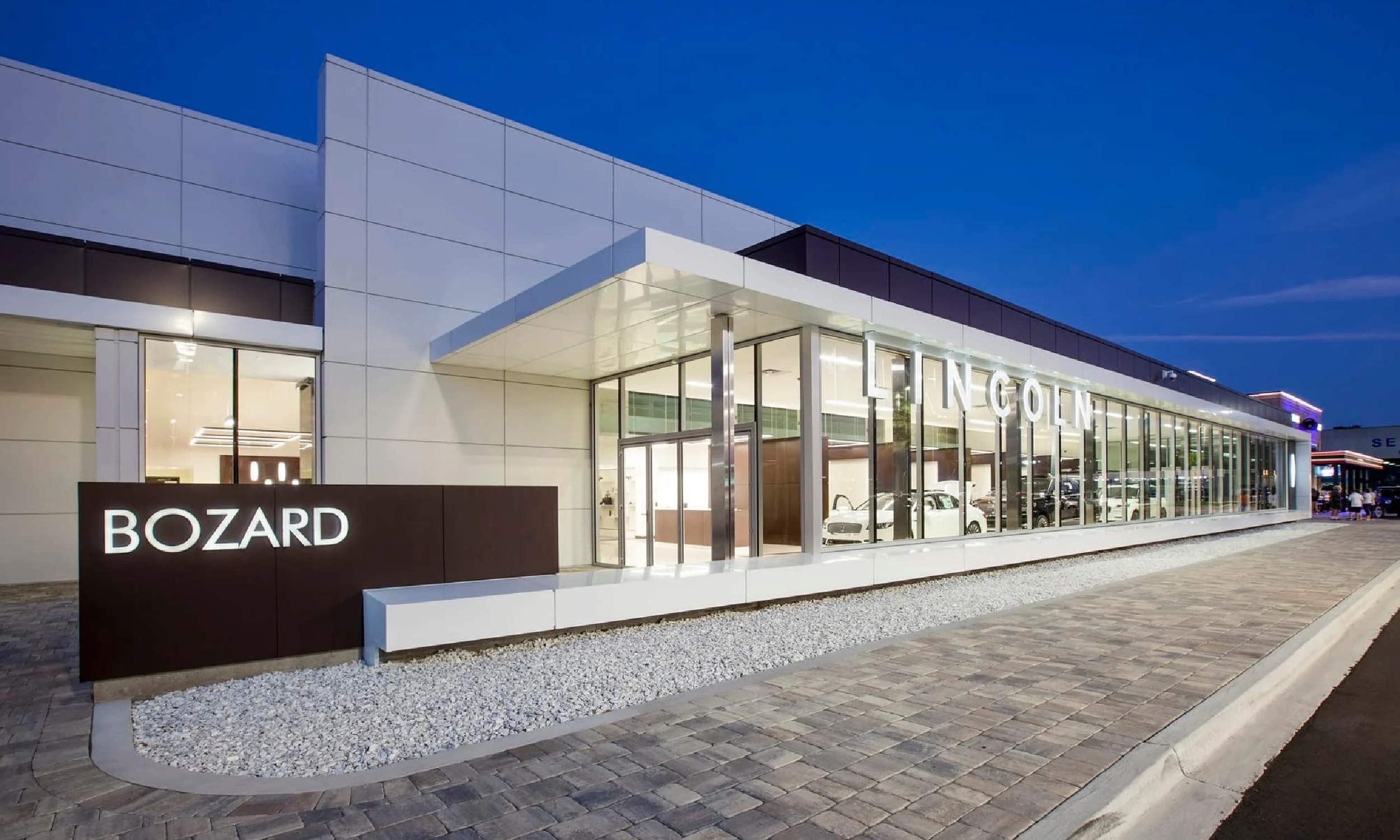 The Bozard Lincoln Showroom, a modern white and glass building, against a dusky blue sky