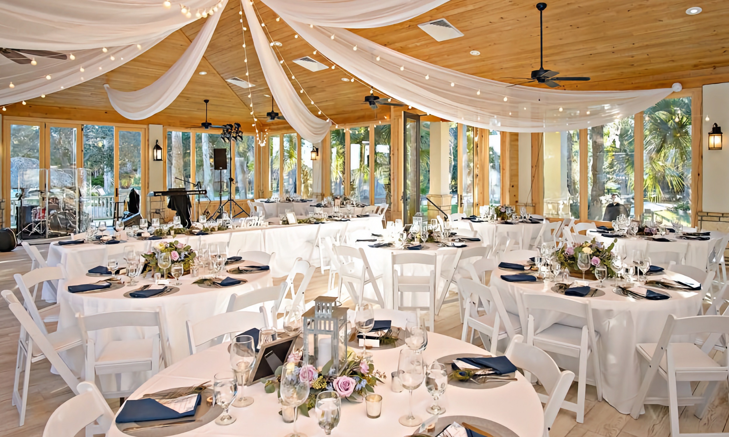 The Magnolia Room decorated for a reception, with white drapery decorating the cieling and round tables filled with table settings.