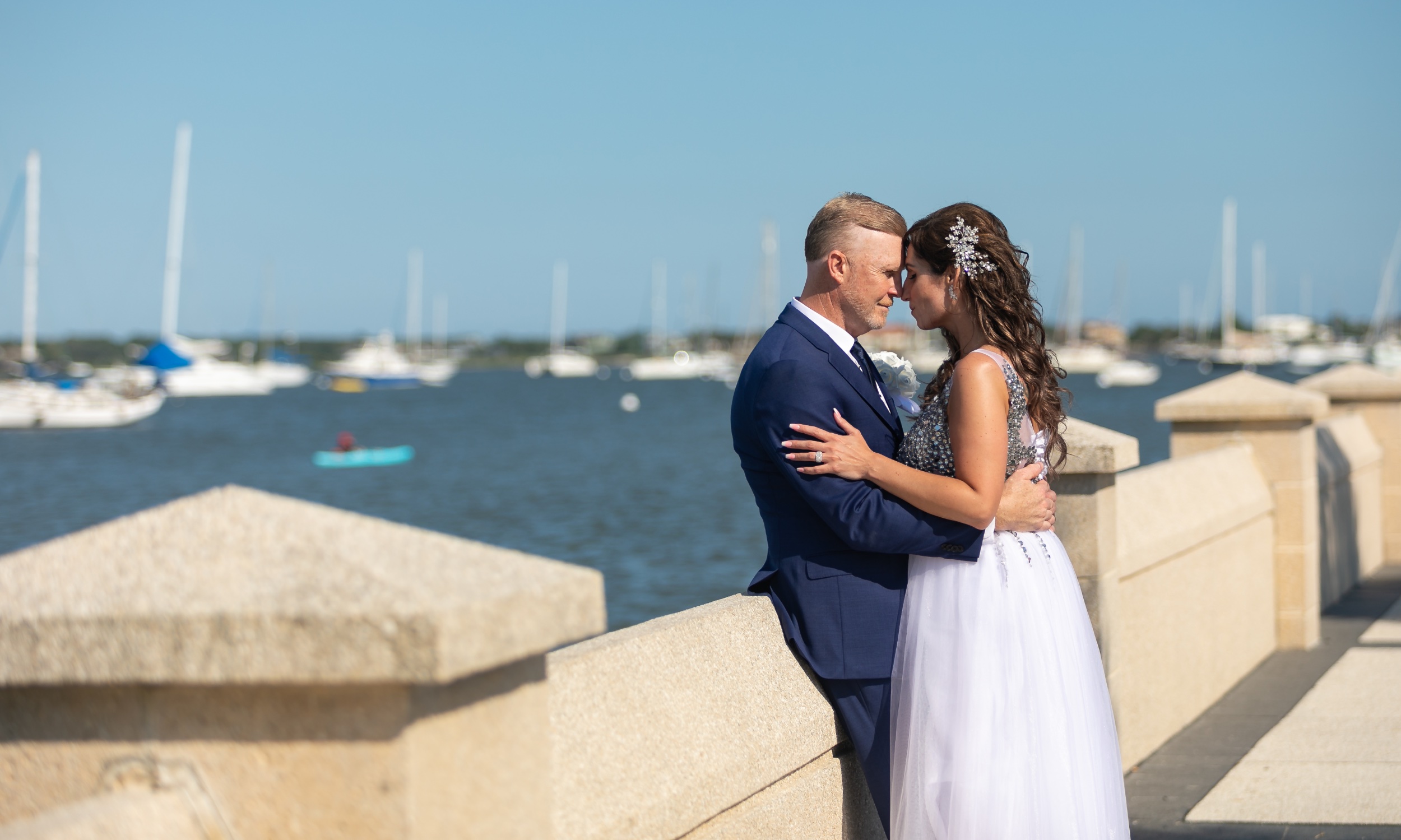 A wedding couple leaning on the wall along the bayfront