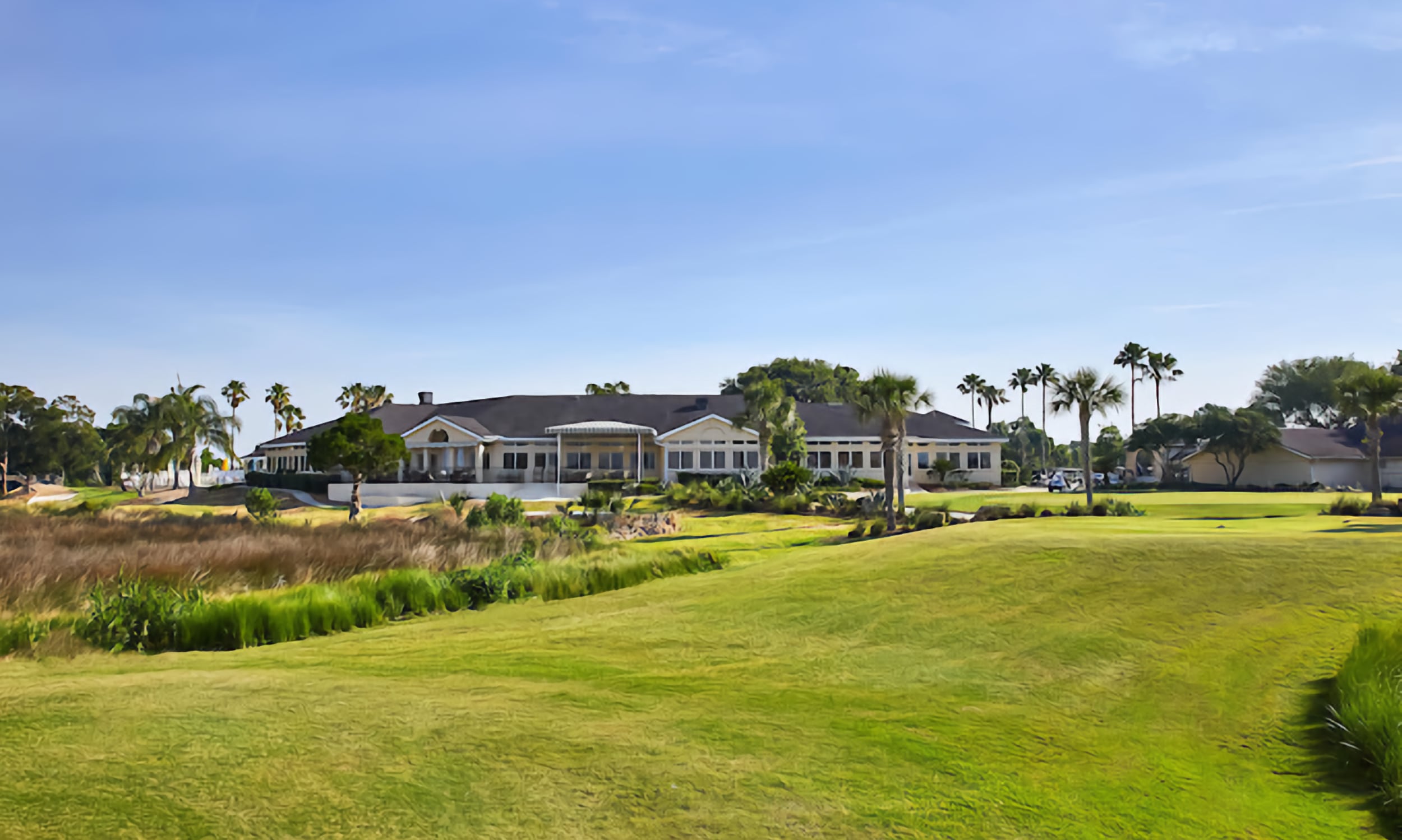 Marsh Creek Country Club's clubhouse stands amidst palm trees, overlooking the rolling green fairway
