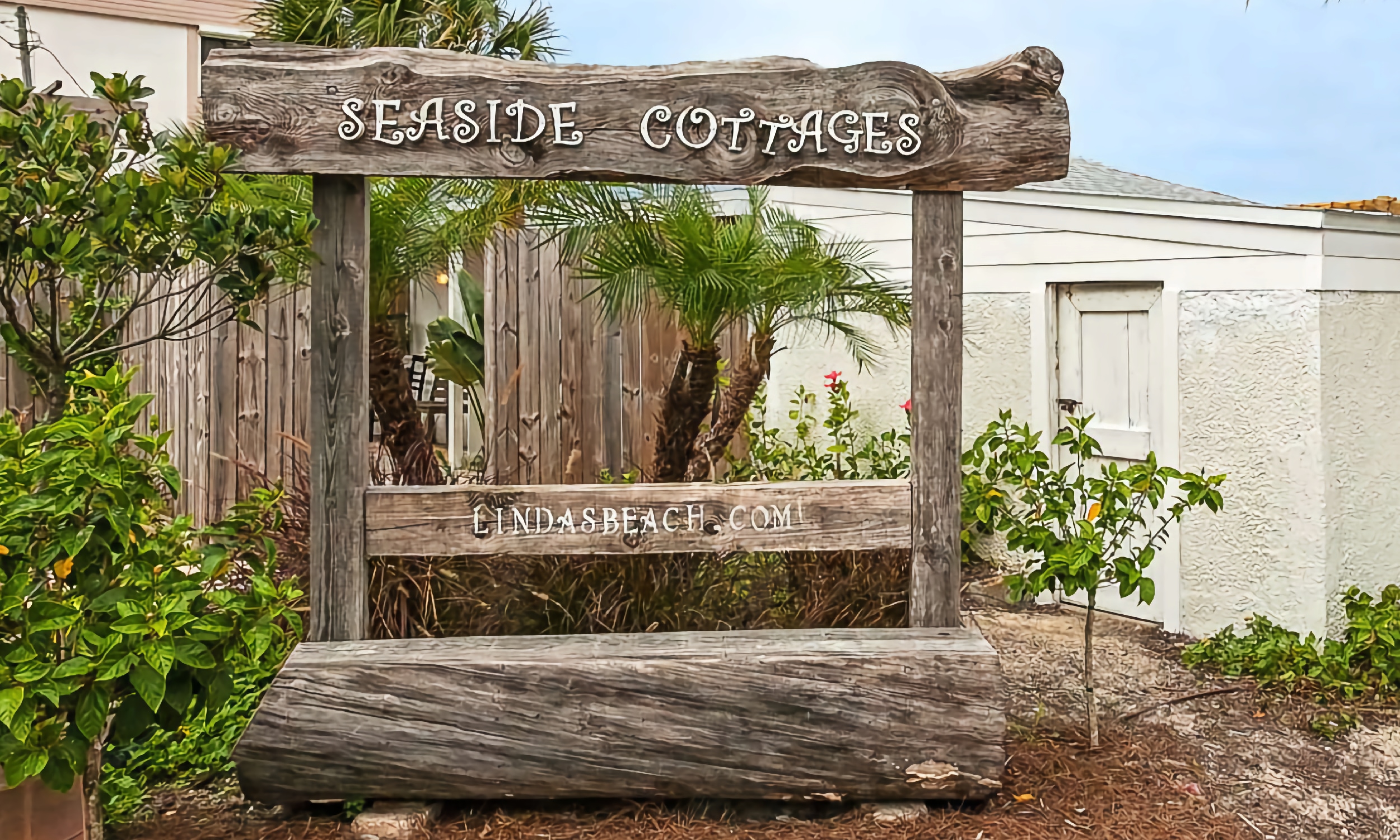 A large rustic wood sign welcomes guests to Linda's Beach Vacation Rentals on the beach