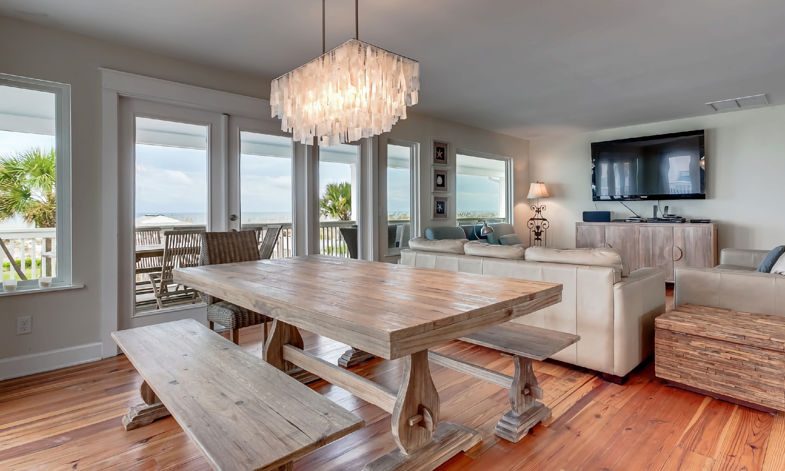 The greatroom in a cottage on the beach, with a dining table, sofa and seating area, and the view of the ocean