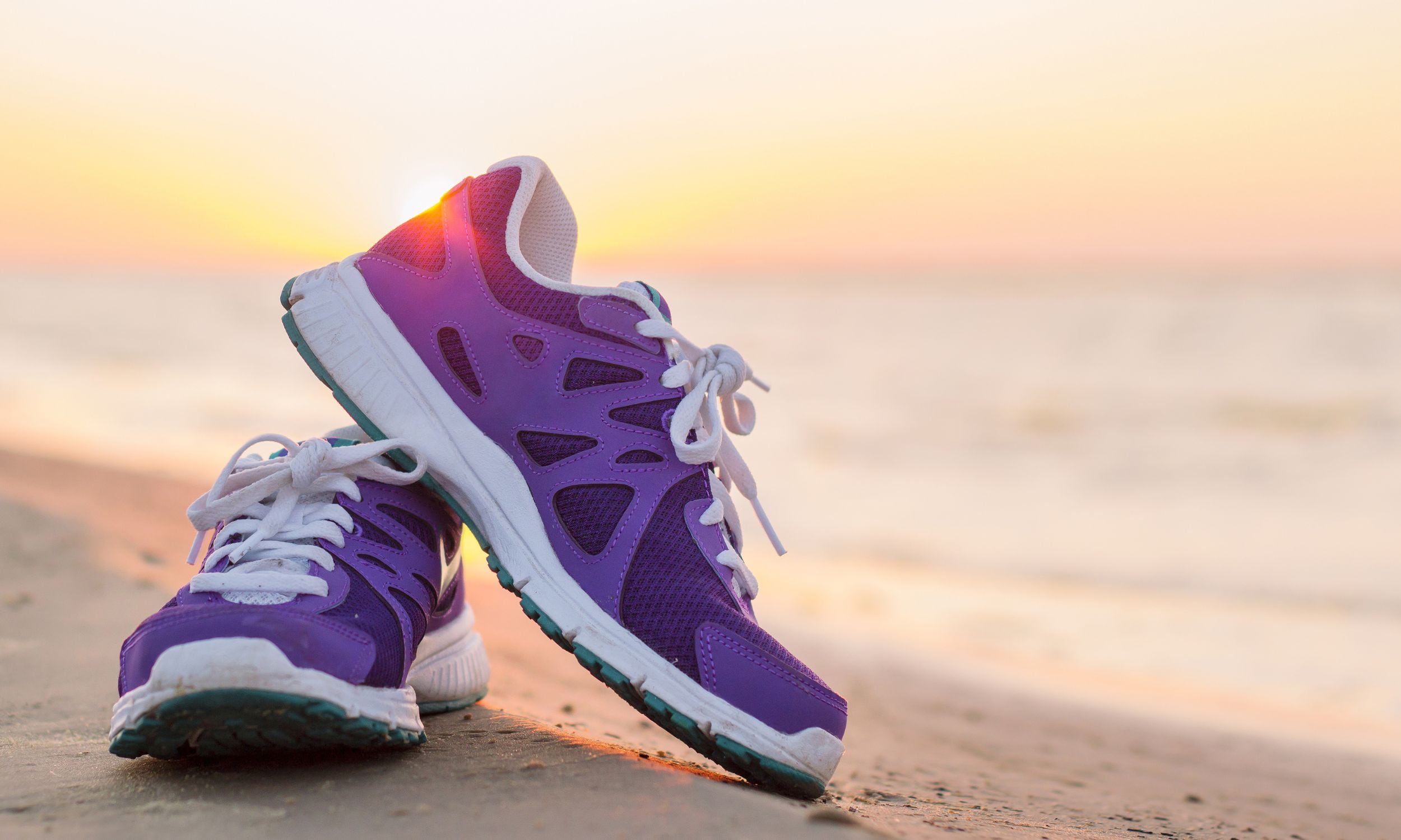 Purple running shoes sitting in front of the ocean