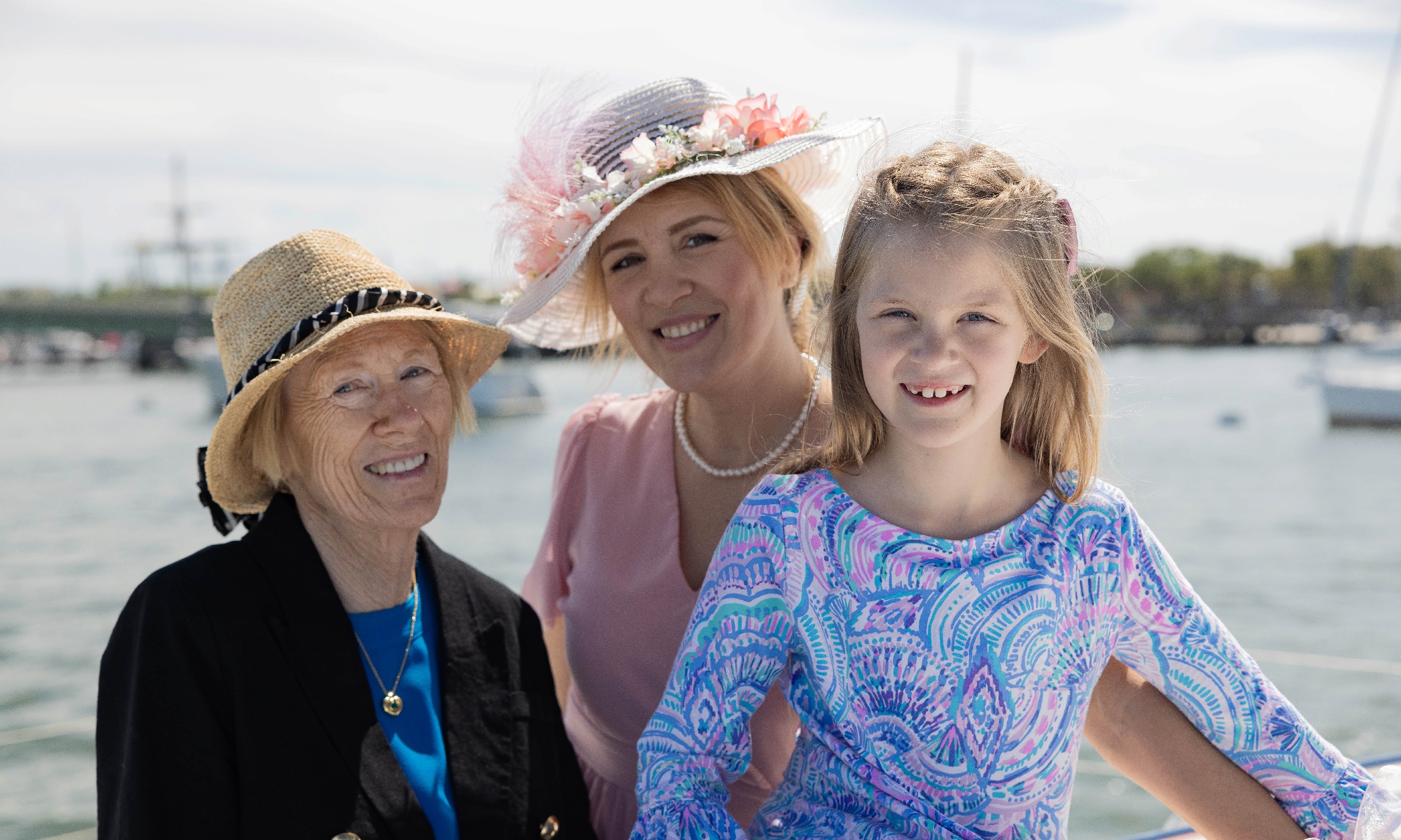 Three generations, a grandmother, mother, and daughter dressed for tea aboard a catamaran