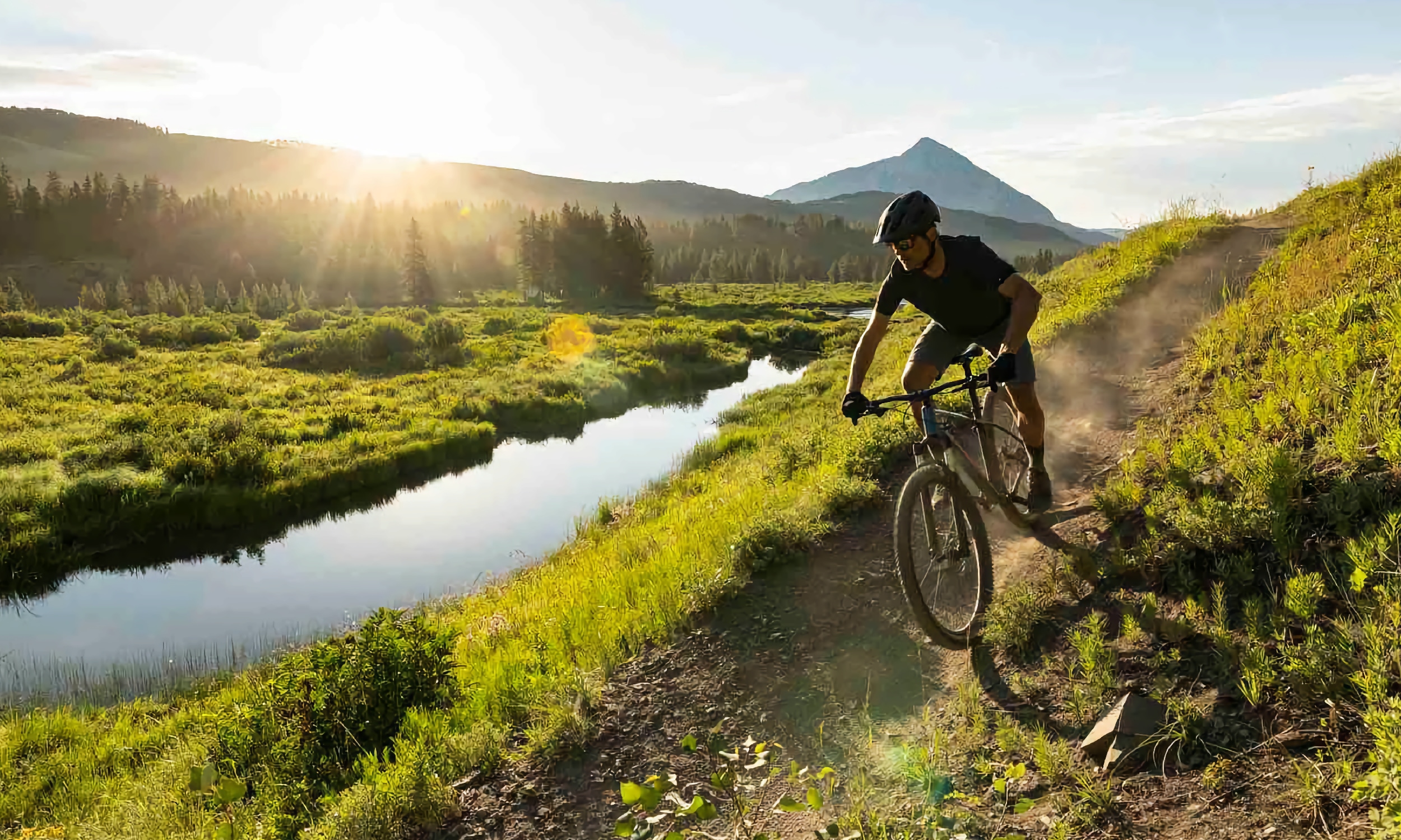 A lone cyclist on a mountain trail near a river