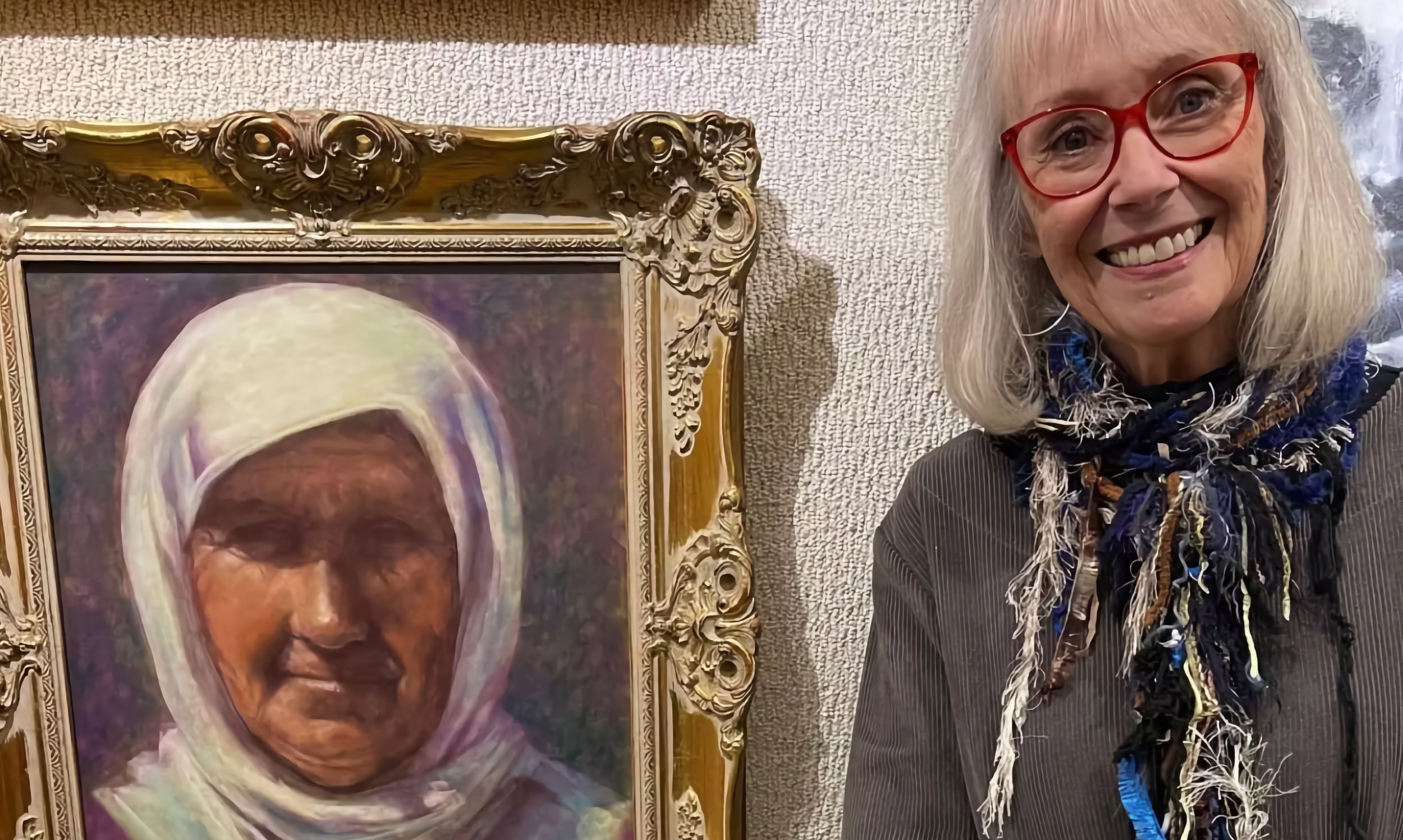 Artist, Cynthia Pierson posing next to one of her realism portraits