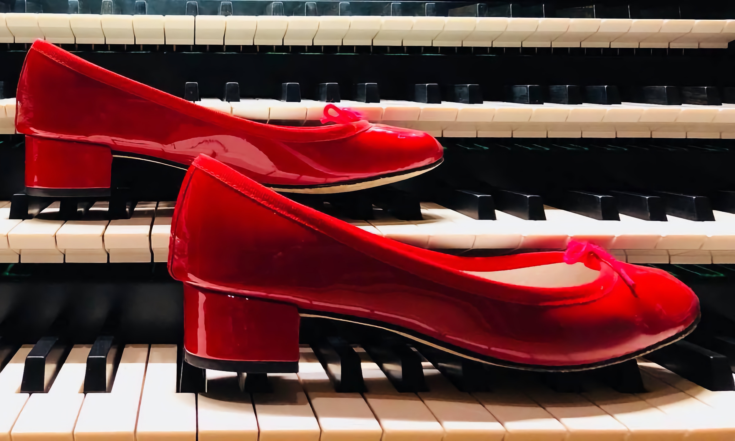 A pair of red shoes placed on two rows of keys on a large organ
