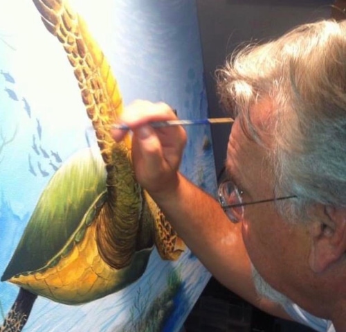Artist Stewart Maxcy painting a swimming sea turtle on canvas