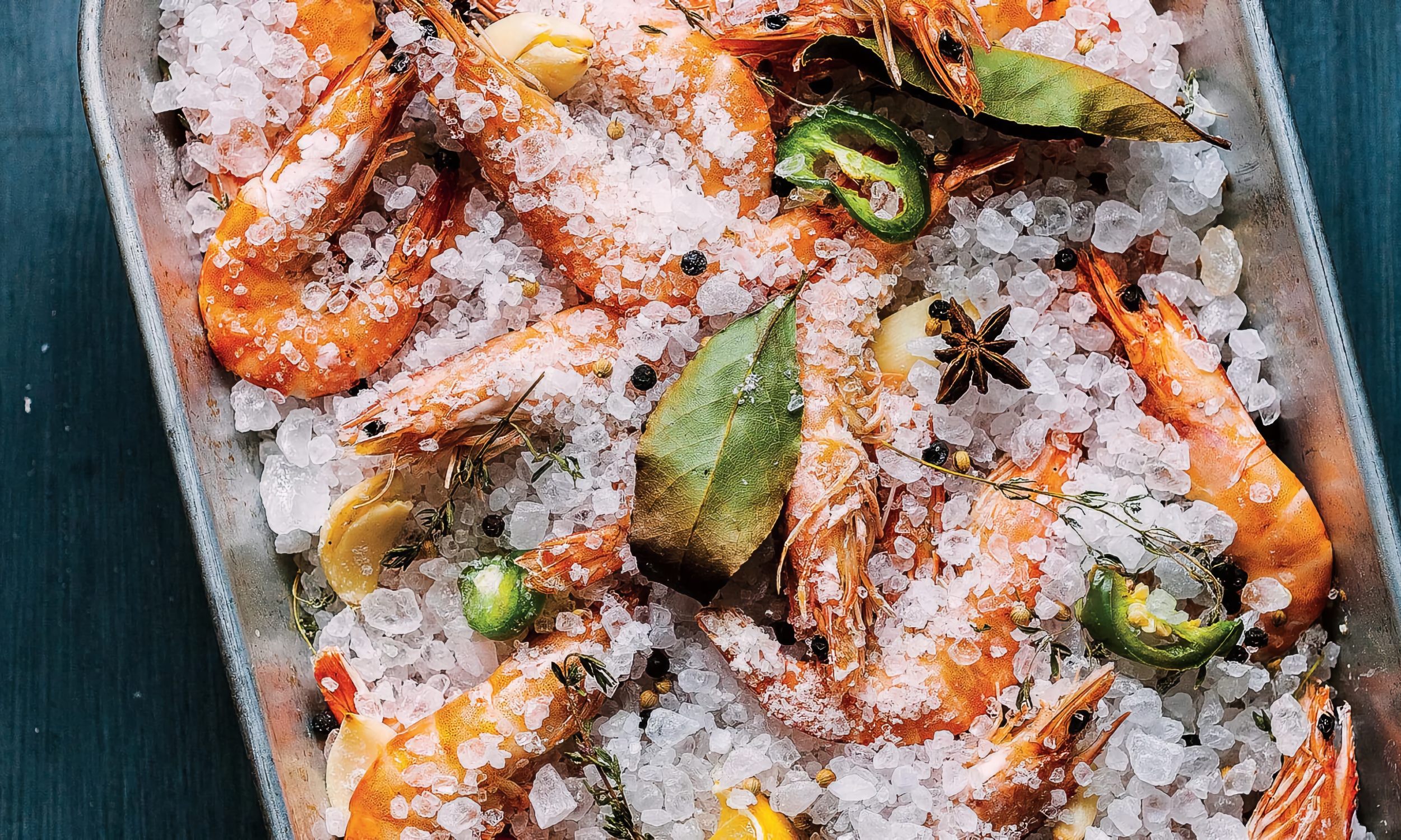 A pan of shrimp covered in herbs and rock salt