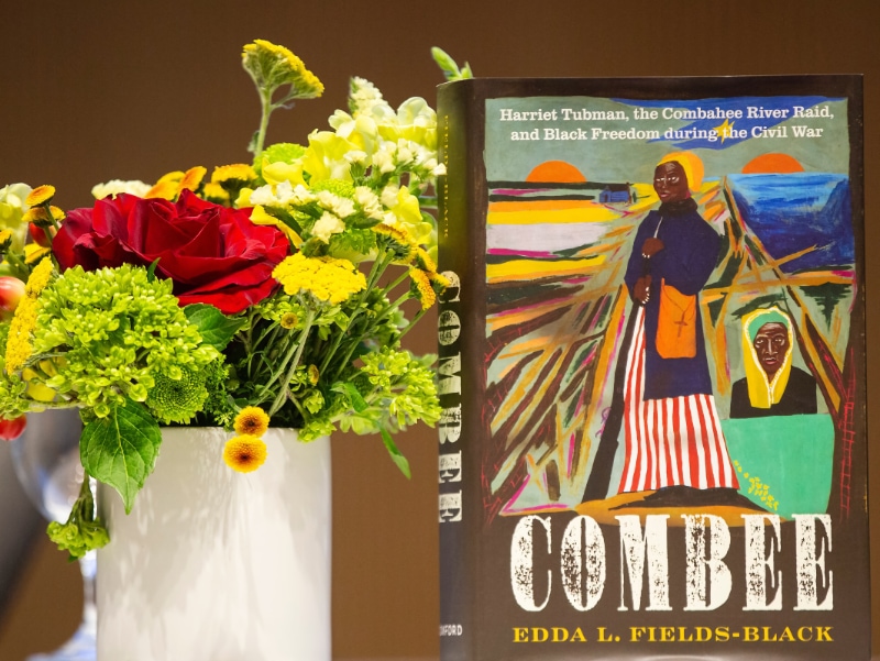 The book, COMBEE standing next to a vase of flowers