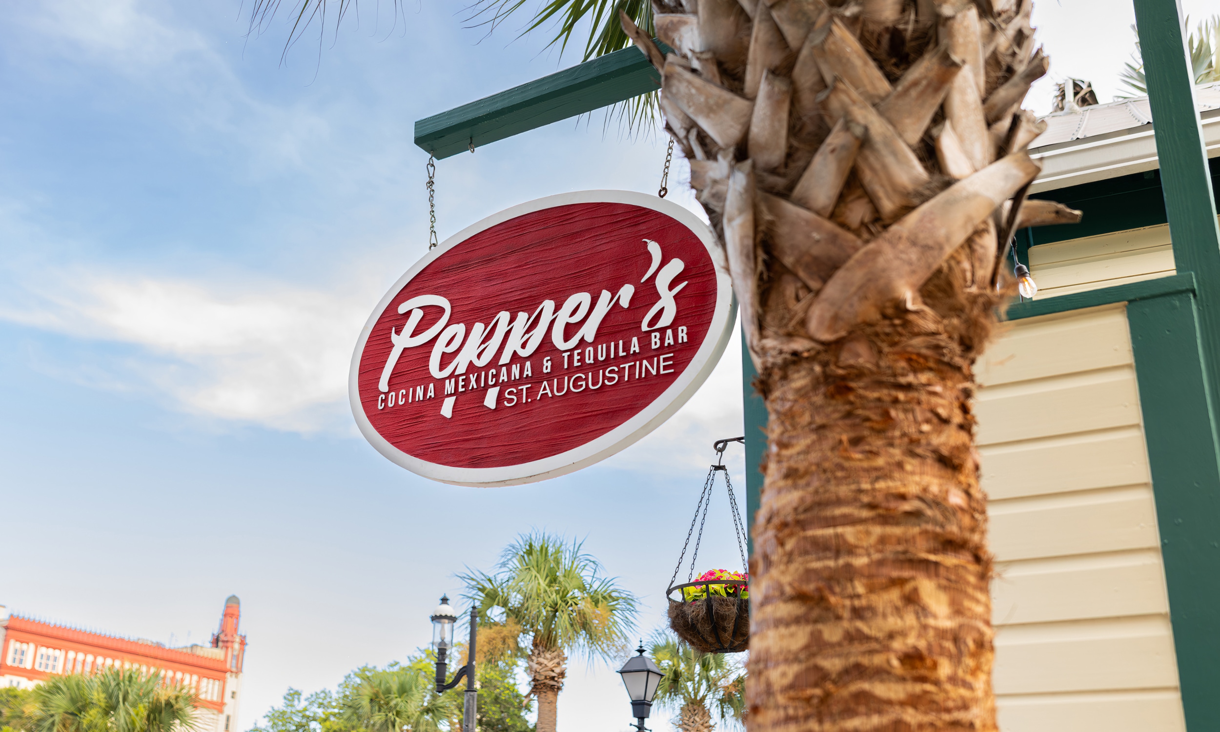 The hanging sign at Peppers against a blue sky with wispy clouds