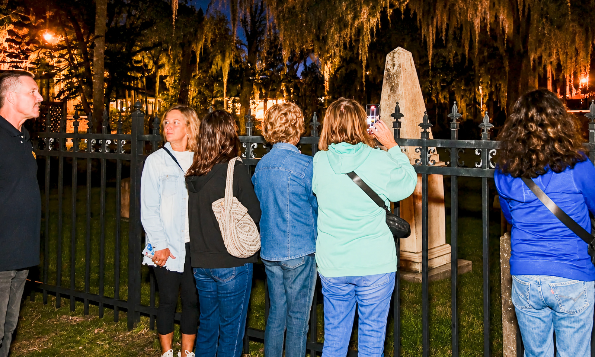 A tour group at the gates of the Tolomato cemetery at night