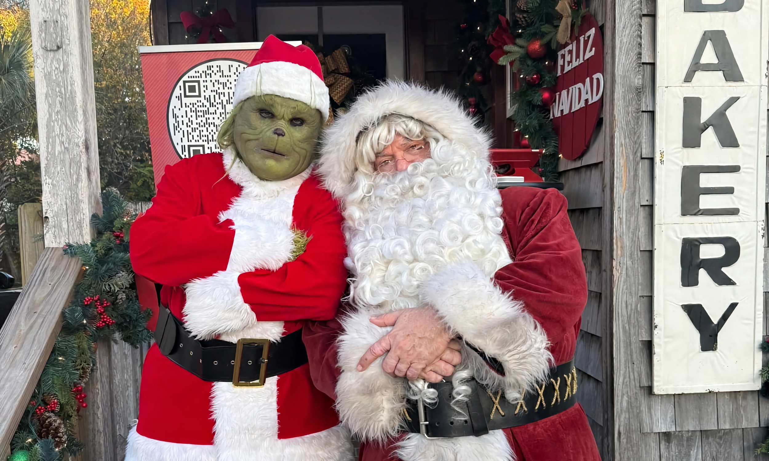 A grinch in a Santa Suit and a Santa standing side by side