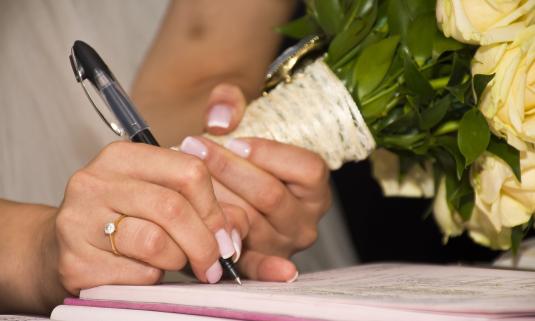 A bride signing the marriage record. (Photo courtesy of Pixabay.)