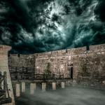 A photo of the gate to the Castillo at night, under a stormy sky