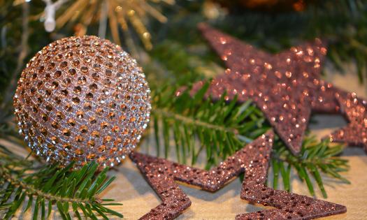 Glittery bronze Christmas ball and star ornaments nestled in green boughs
