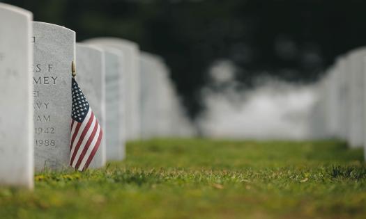 A flag rests on a headstone in a National Cemetery. 