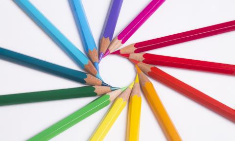 Sharpened art pencils in rainbow colors, arranged with their points to form a circle