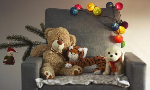 A trio of stuffed animals sit in a armchair, apparently ready for holiday stories