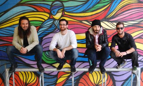 The band poses with a colorful background.