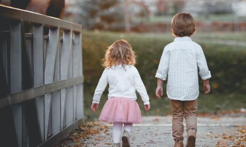 Two young children, a boy and girl, walking along a boardwalk