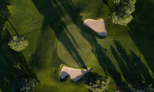An over head shot of a golf area is captured on a sunny day. 