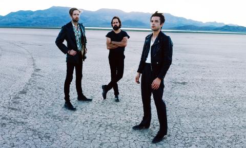 The Killers standing on an arid, flat landscape