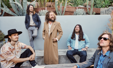 Members of the band smile and pose in their jackets.