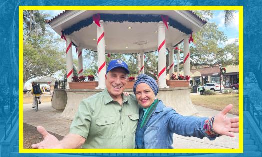 Two people in welcoming posture standing in front of the Gazebo in St. Augustine