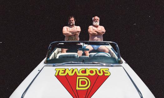 Jack Black and Kyle Gass in swimsuits sitting in the back of a white convertible