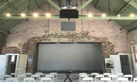 The interior of the Waterworks, with empty chairs, and a movie screen on the stage