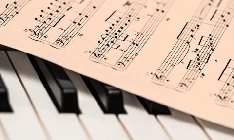 Clip art of sheet music draped over the keys of a piano