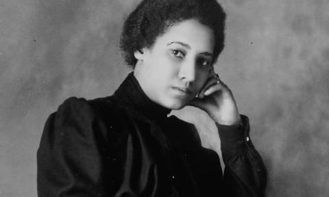 An African American woman poses on a black and white photo.