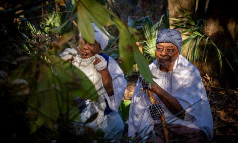 Two female interpreters at Fort Mose in St. Augustine Florida crouch in the woods