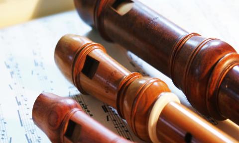 Three wooden recorders placed on an open music score