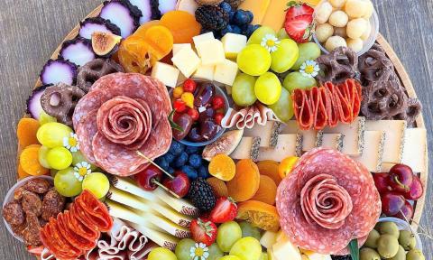 A beautiful charcuterie board filled with meats, cheeses, vegetables, and fruits
