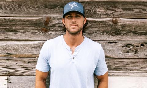 Riley Green poses in front of a wood backdrop