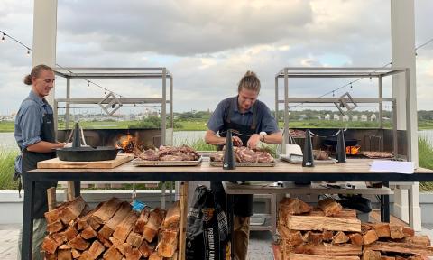 Two chefs at the live-fire grill, outdoors on the patio of the restaurant located on the San Sebastian River in St. Augustine