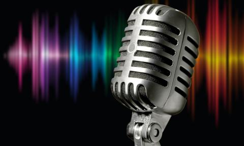 A voice microphone against a black background that is highlighted by multi-colored stage lights