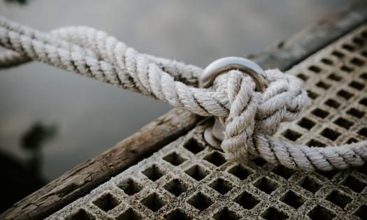 A knot is connected from a deck to a boat. 